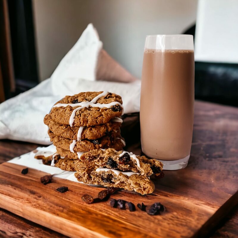 Stack of uneaten choc chip cookies next to a tall glass of chocolate milk.