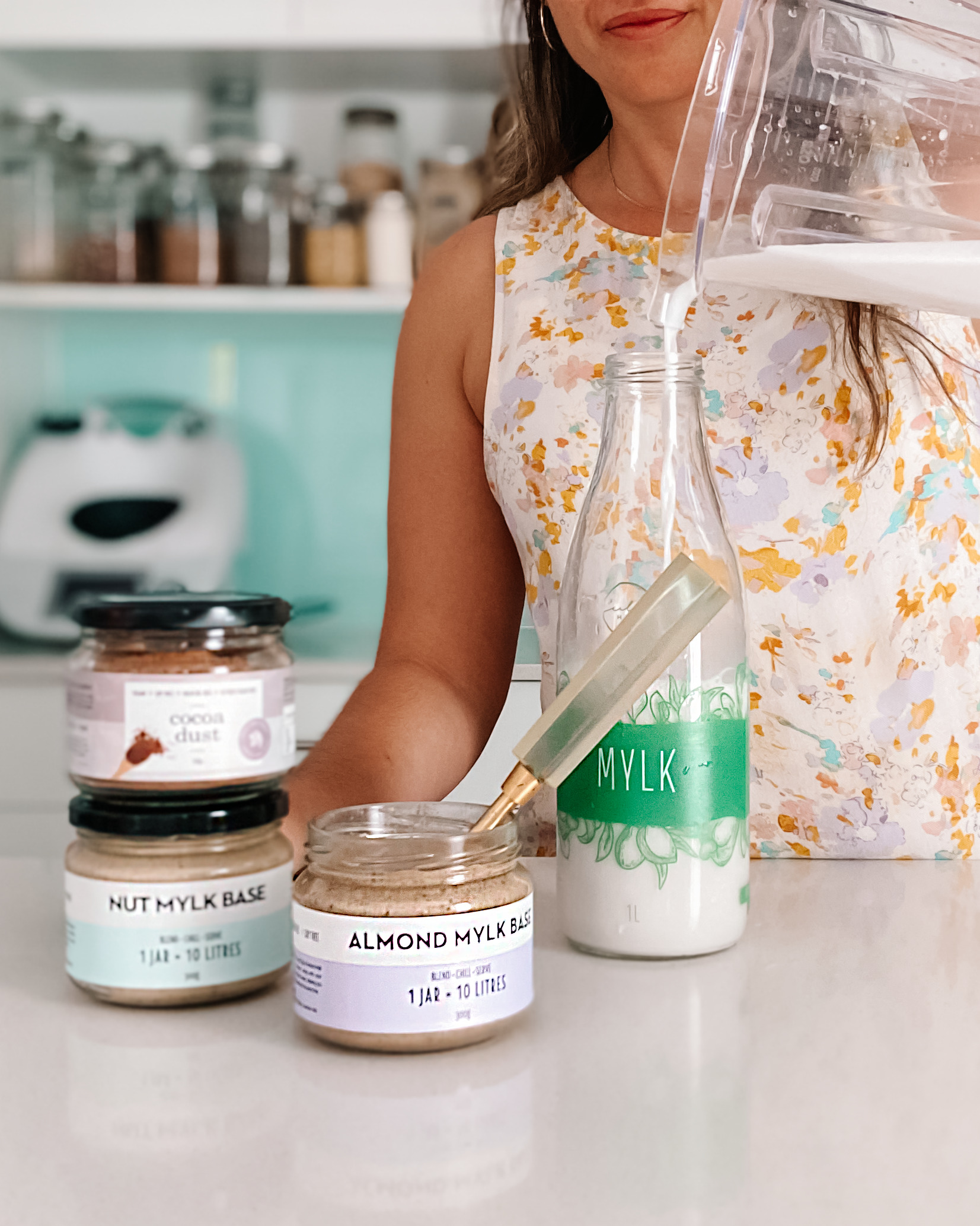 Woman pouring freshly made milk into a glass milk bottle on a kitchen bench