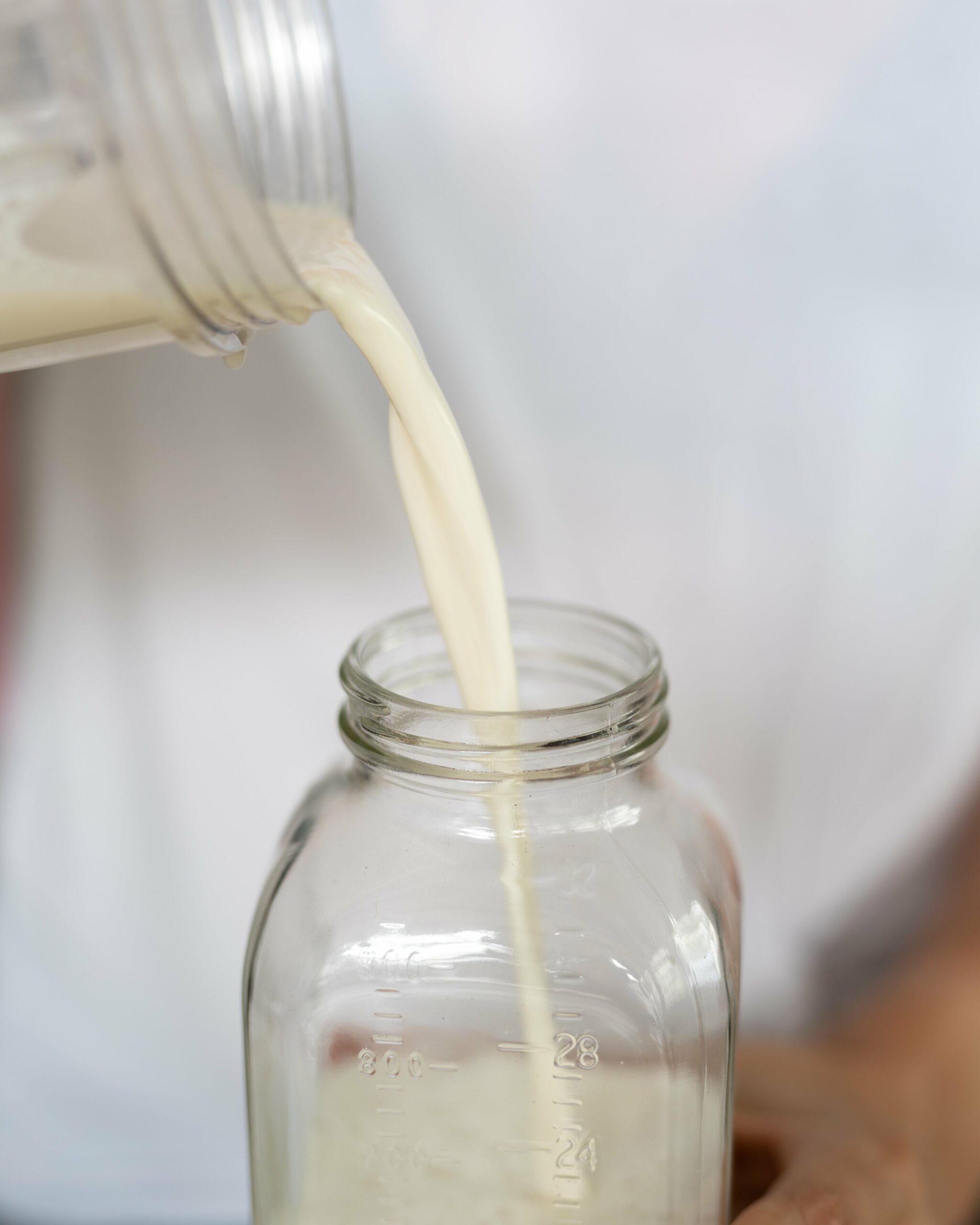 Pouring freshly made milk into a glass bottle