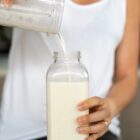 Woman pouring freshly made milk into a clear glass container