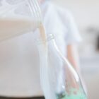 Woman pouring freshly made milk into glass bottle.